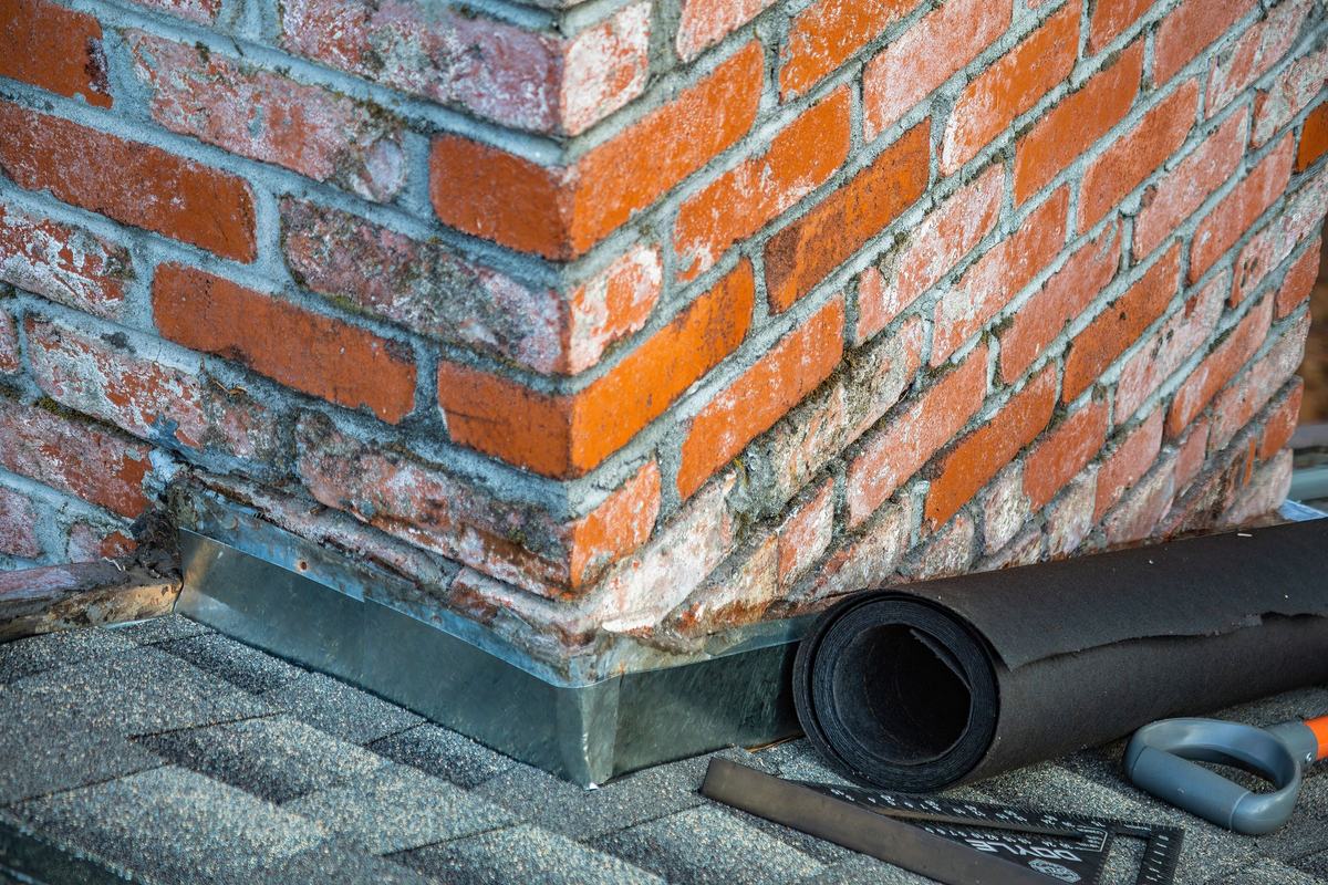 Brick chimney base with metal flashing where it meets the roof