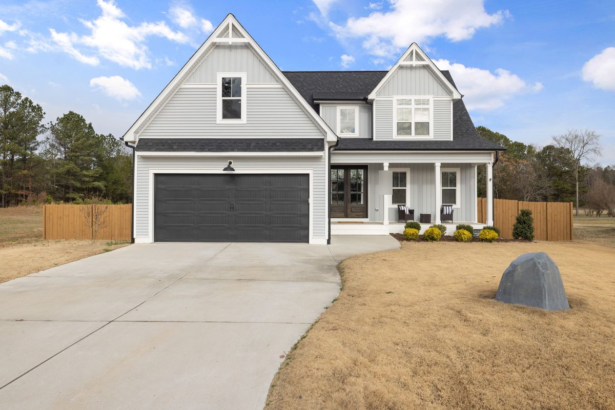 New two-story home with gray siding, a front porch and a two-car garage